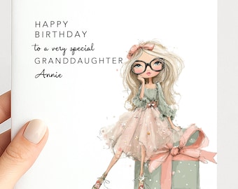 May include: A square greeting card featuring a blonde character wearing black glasses, a green top, and a pink tulle skirt. The text reads: HAPPY BIRTHDAY to a very special GRANDDAUGHTER Annie. The character sits on a green gift box with a pink bow.