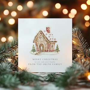May include: A square white greeting card featuring a watercolor illustration of a gingerbread house with white icing, red and white candy canes, and two small green pine trees. The text reads: MERRY CHRISTMAS to you and your family FROM THE SMITH FAMILY.