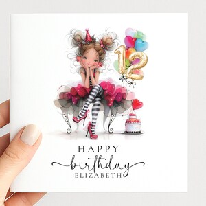 May include: A square greeting card featuring a cartoon illustration of a girl with brown hair in buns, wearing a red party hat, a pink and black tutu, and striped leggings. Gold number 12 balloons, colorful balloons, and a cake are present. Text reads HAPPY birthday ELIZABETH.