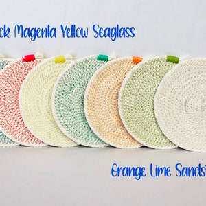May include: Set of six round woven coasters with colorful trim. The colors are peacock, magenta, yellow, seaglass, orange, and lime. The coasters are labeled "Peacock Magenta Yellow Seaglass" and "Orange Lime Sandstone".