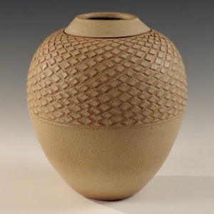 Könnte beinhalten: Eine beige Keramikvase mit einem strukturierten, rautenförmigen Muster um die Mitte.