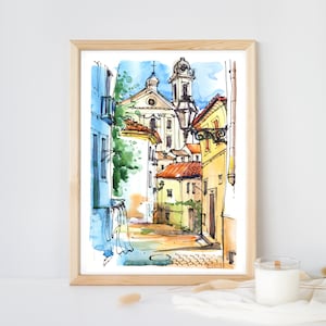 Puede incluir: Pintura acuarela de una calle estrecha en una ciudad europea. La calle está bordeada de edificios coloridos, incluida una iglesia con un alto campanario. La pintura está realizada en un estilo suelto e impresionista.
