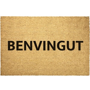 May include: A brown coir doormat with the word "BENVINGUT" in black lettering.