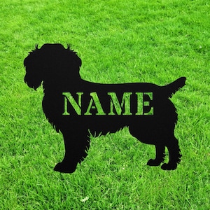 May include: Black metal silhouette of a dog with the word "NAME" in the middle of the silhouette. The silhouette is on a green grassy lawn.