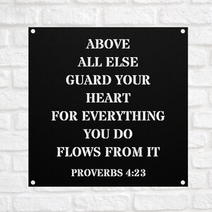 May include: Black metal sign with white text that reads "Above all else guard your heart for everything you do flows from it Proverbs 4:23".