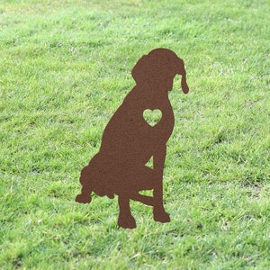 May include: A brown metal silhouette of a dog sitting with a heart cut out of its chest. The silhouette is on a green grassy lawn.