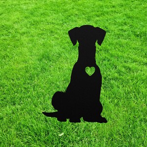 May include: Black metal silhouette of a dog sitting with a heart cutout on its chest. The silhouette is on a green grassy lawn.