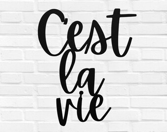 May include: Black metal wall decor with the French phrase "C'est la vie" written in a cursive font.