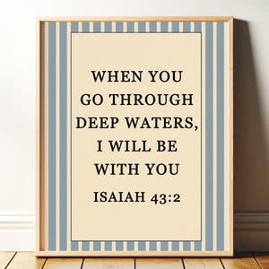 May include: Framed print with the text "WHEN YOU GO THROUGH DEEP WATERS, I WILL BE WITH YOU ISAIAH 43:2". The print has a cream-colored background with black text, framed by a light blue and white striped border.