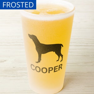 May include: A frosted glass with a silhouette of a dog and the name "COOPER" printed on it. The glass is filled with a light yellow beverage.