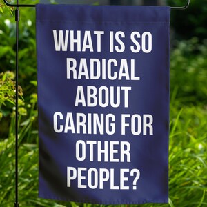 May include: A blue garden flag with white text that reads "What is so radical about caring for other people?"