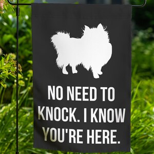 May include: Black garden flag with a white silhouette of a Pomeranian dog. The text "NO NEED TO KNOCK. I KNOW YOU'RE HERE." is printed in white.