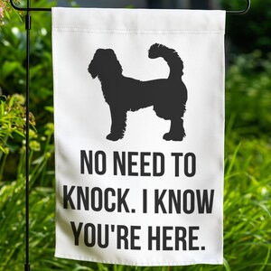 May include: A white garden flag with a black silhouette of a dog with the text "NO NEED TO KNOCK. I KNOW YOU'RE HERE."