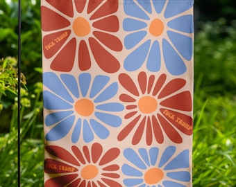 May include: A garden flag featuring a repeating floral pattern in shades of rust, light blue, and orange, with the text "FUCK TRUMP" in a bold font. The flag is displayed outdoors.