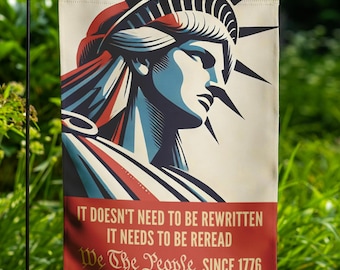 May include: A garden flag featuring a stylized illustration of the Statue of Liberty in red, white, and blue. The flag has text that reads "IT DOESN'T NEED TO BE REWRITTEN IT NEEDS TO BE REREAD We The People SINCE 1776."