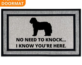 May include: Rectangular all-weather doormat with a black border and a light gray center. The center features a black silhouette of a dog and the text "NO NEED TO KNOCK... I KNOW YOU'RE HERE."