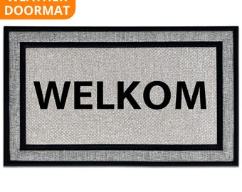 May include: Rectangular all-weather doormat with the word "WELKOM" in large black letters. The mat has a light gray woven center, a black border, and a black frame. The top left corner has an orange label that says "ALL WEATHER DOORMAT".