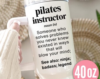 May include: White 40 oz tumbler with a handle, featuring the text "pilates instructor" and a definition. The definition describes a problem-solver. A pink circle on the bottom right indicates the tumbler's capacity.