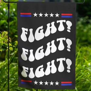 May include: A black garden flag with a white, wavy font that reads "FIGHT!" three times. The flag has a red, white, and blue stripe at the top and bottom with white stars.