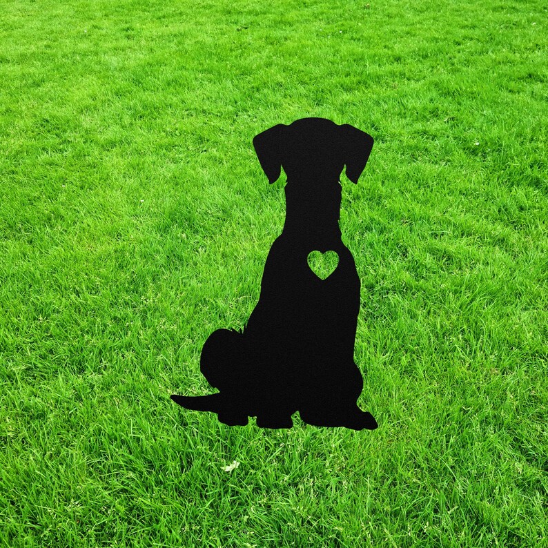 May include: Black metal silhouette of a dog sitting with a heart cutout on its chest. The silhouette is on a green grassy lawn.