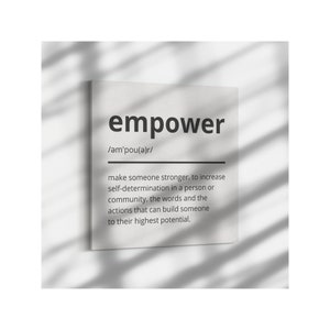 May include: A black and white print with the word "empower" in bold, followed by the phonetic pronunciation and a definition of the word. The definition explains that empower means to make someone stronger and increase self-determination in a person or community.