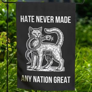 May include: Black and white illustration of a cat with a snake wrapped around its neck. The text "Hate Never Made Any Nation Great" is printed on the black background.