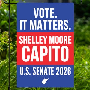 May include: A rectangular political garden flag featuring a blue top and bottom section with white text reading VOTE. IT MATTERS. and U.S. SENATE 2026, with a central red band displaying the white text SHELLEY MOORE CAPITO and a small white map outline.