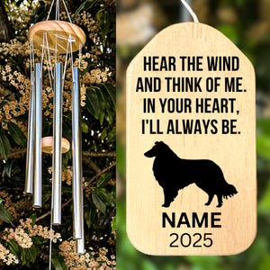 May include: A wind chime with silver tubes and a wooden top, hanging in front of a tree. A wooden tag with the text "HEAR THE WIND AND THINK OF ME. IN YOUR HEART, I'LL ALWAYS BE." and a dog silhouette.