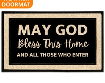 May include: Black rectangular all-weather doormat with a gold border. The mat features the text "MAY GOD Bless This Home AND ALL THOSE WHO ENTER" in gold lettering. An orange banner in the upper left corner reads "ALL WEATHER DOORMAT".