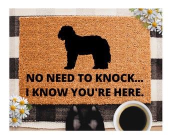 May include: A rectangular doormat with a black and white checkered border. The mat features a silhouette of a dog and the text "NO NEED TO KNOCK... I KNOW YOU'RE HERE." White daisies are in the corners.