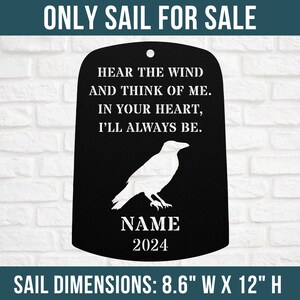 May include: Black metal memorial sail with a white raven silhouette and the text "Hear the wind and think of me. In your heart, I'll always be."  The sail also includes a name and the year 2024. The sail dimensions are 8.6 inches wide by 12 inches high.