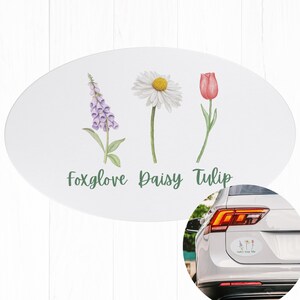 May include: Oval white car sticker featuring watercolor illustrations of a foxglove, daisy, and tulip. The flowers are accompanied by the text "foxglove Daisy Tulip" in green script. A car with a similar sticker is shown.