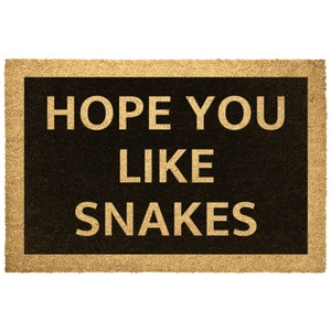 May include: A brown doormat with a black border and the text "HOPE YOU LIKE SNAKES" in gold lettering.