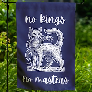 May include: A blue garden flag with a white cat holding a snake in its mouth. The text "no kings no masters" is printed on the flag.