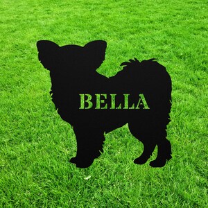 May include: Black silhouette of a dog with the name "BELLA" written on it. The silhouette is on a green grassy background.