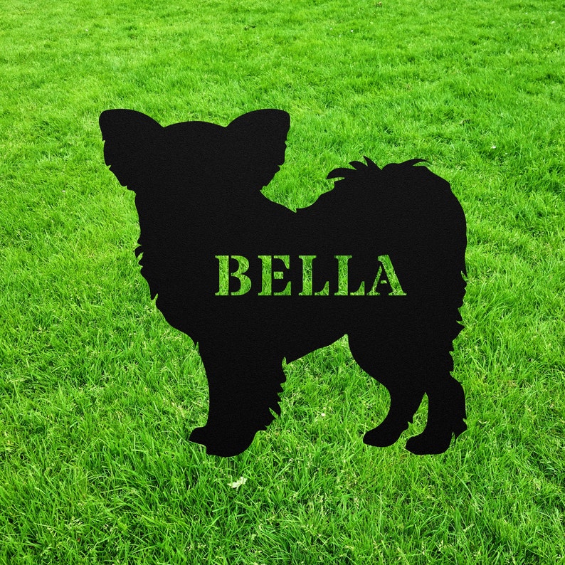 May include: Black silhouette of a dog with the name "BELLA" written on it. The silhouette is on a green grassy background.