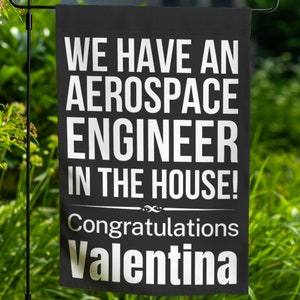 May include: Black and white garden flag with the text "We have an aerospace engineer in the house! Congratulations Valentina".