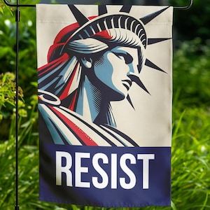 May include: A garden flag with a stylized image of the Statue of Liberty in red, white, and blue colors. The flag has the word "RESIST" printed in white letters on a blue background.