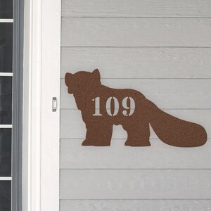May include: A brown silhouette of a bear with the number 109 printed on its side. The bear is mounted on a light gray wooden surface.