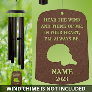 May include: A brown wooden memorial plaque with a green silhouette of a bird. The plaque has the text "Hear the wind and think of me. In your heart, I'll always be." and a space for a name and year. The text "Wind chime is not included" is at the bottom of the image.