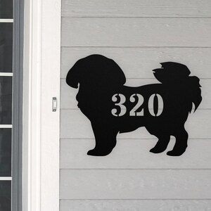 May include: Black metal silhouette of a dog with the house number 320 cut out of the dog's body. The dog is standing on a gray wooden surface.