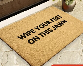 May include: A brown coir doormat with the text "Wipe your feet on this Jawn" in black lettering. The doormat is available in four sizes.