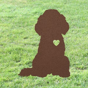 May include: A brown metal silhouette of a dog sitting with a heart cut out of its chest. The silhouette is on a green grassy background.