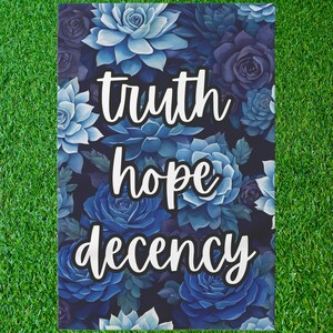 May include: A garden flag with a blue floral pattern and the words "truth hope decency" in white text.