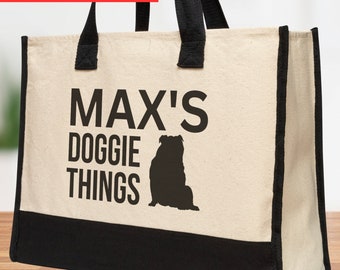 May include: A white canvas tote bag with black handles and trim. The bag has the text "MAX'S DOGGIE THINGS" printed on it in black, along with a black silhouette of a bulldog.