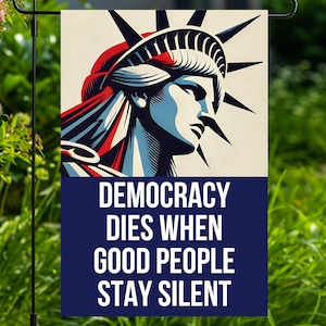 May include: A garden flag featuring a stylized illustration of the Statue of Liberty in red, white, and blue. The flag has the text "DEMOCRACY DIES WHEN GOOD PEOPLE STAY SILENT" in white on a navy blue background.