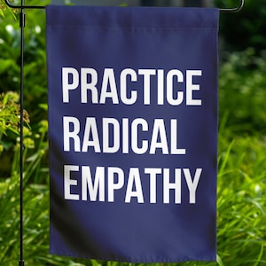 May include: A navy blue garden flag with the text "PRACTICE RADICAL EMPATHY" in white.