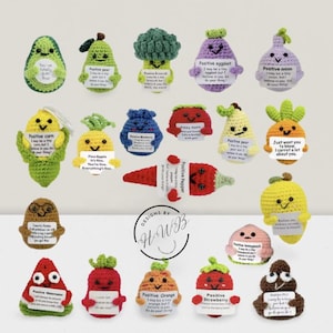 Puede incluir: Una colección de adornos de ganchillo con forma de verduras y frutas, cada uno con una cara sonriente y un pequeño letrero con mensajes positivos. Los adornos incluyen un aguacate, una pera, brócoli, berenjena, cebolla, maíz, piña, arándano, manzana, zanahoria, limón, melocotón, fresa y un emoji de caca.