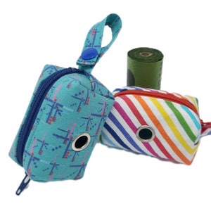 May include: Two colourful dog poo bag dispensers. One is teal with a geometric pattern and the other is rainbow striped. Both have a zipper closure and a hole for dispensing bags.