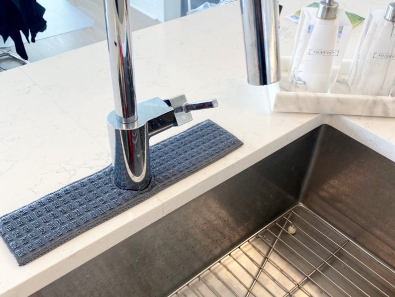 May include: A grey kitchen sink mat with a chrome faucet and a stainless steel sink with a wire rack.